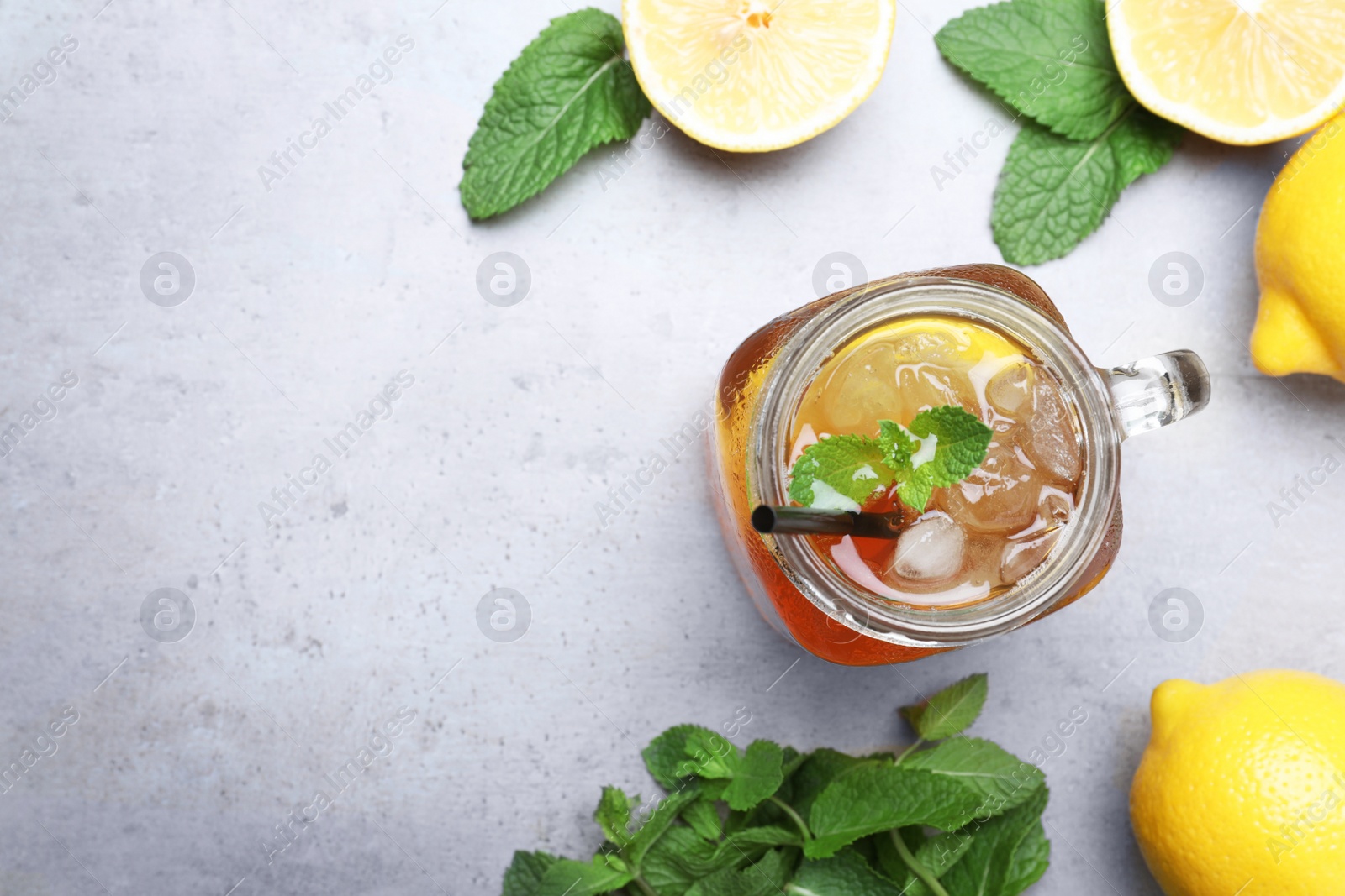 Photo of Delicious iced tea with lemon and mint on grey table, flat lay. Space for text