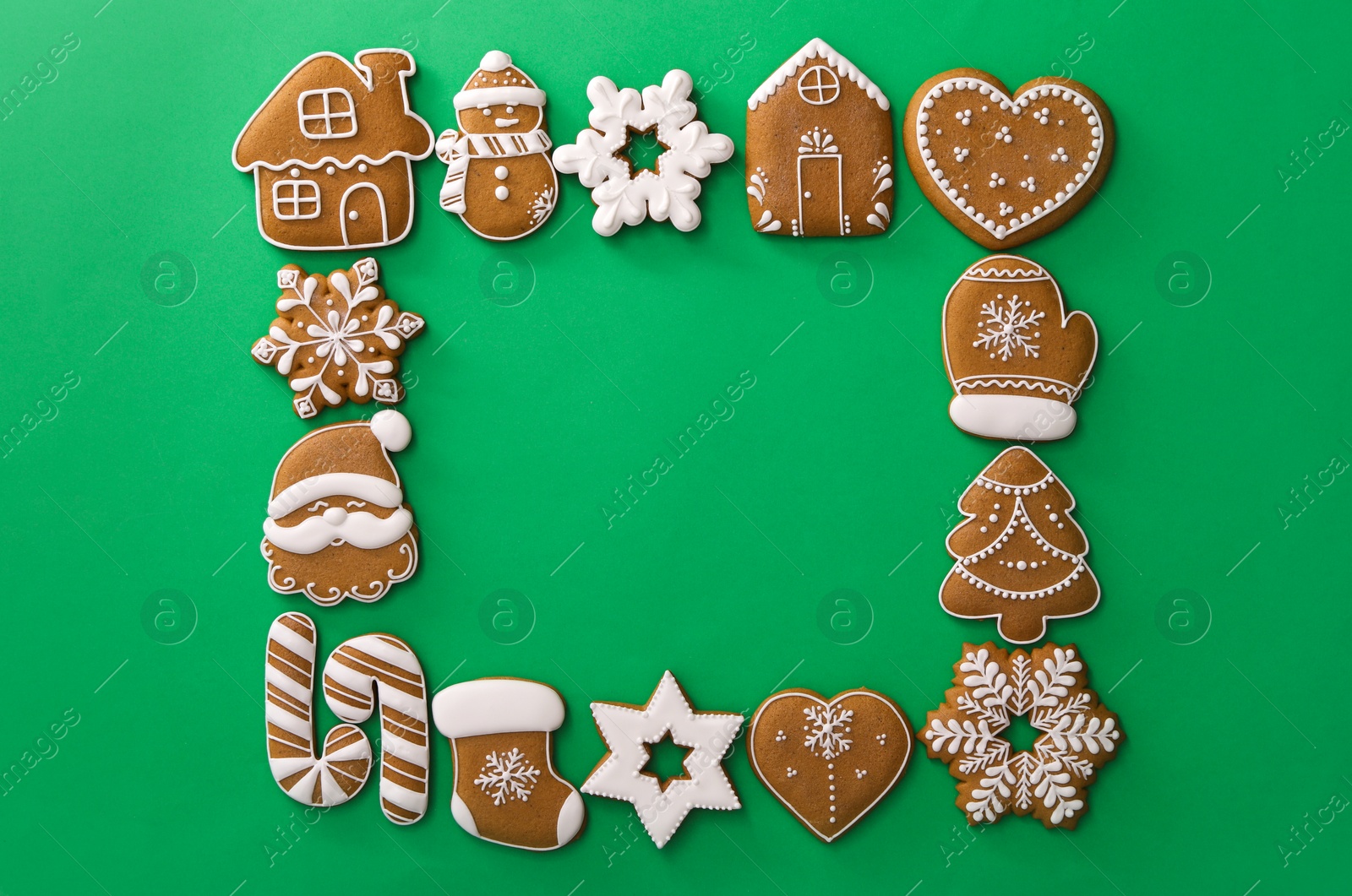 Photo of Frame made with different Christmas gingerbread cookies on green background, top view. Space for text