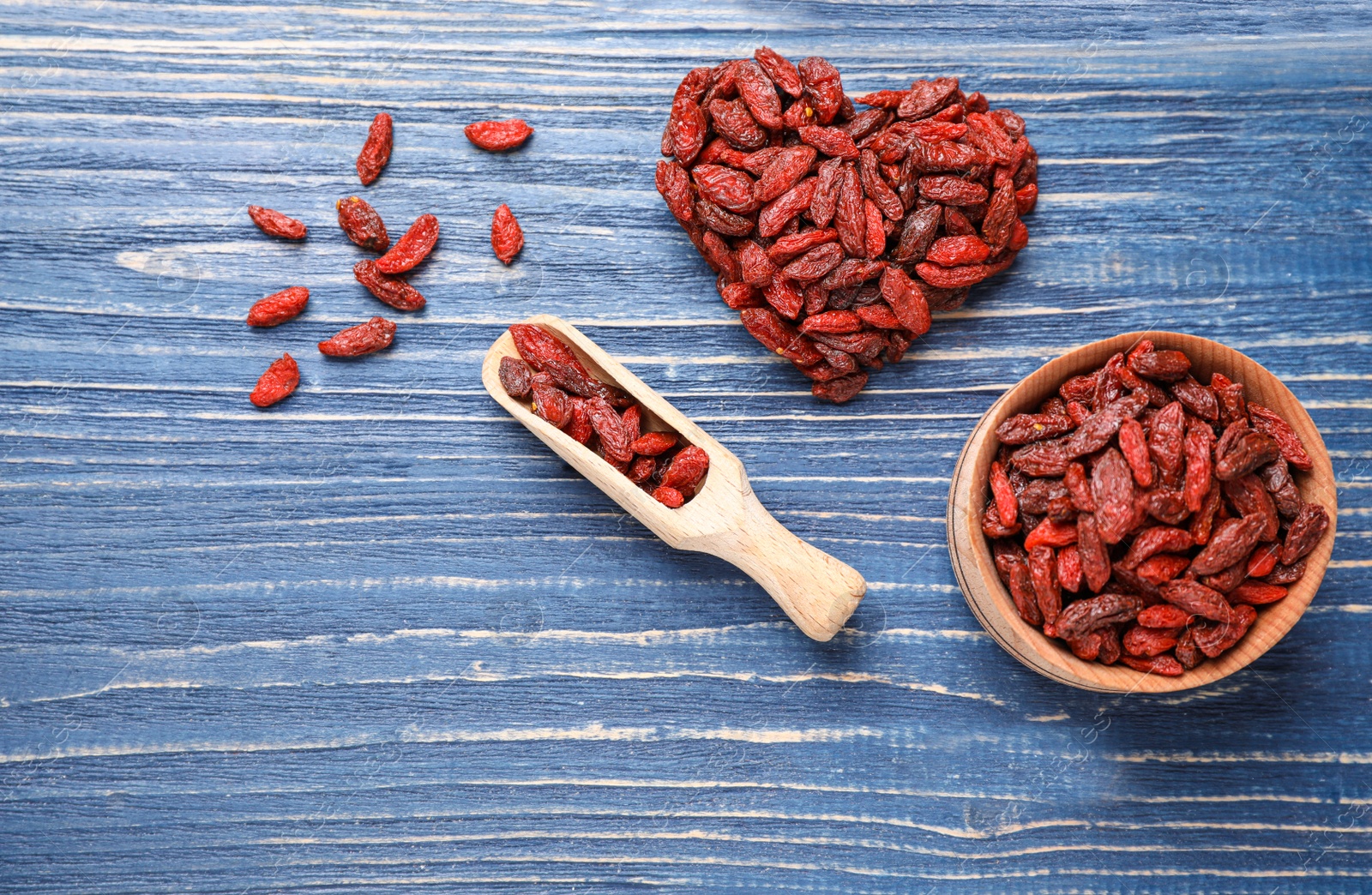 Photo of Flat lay composition with dry goji berries on blue wooden table