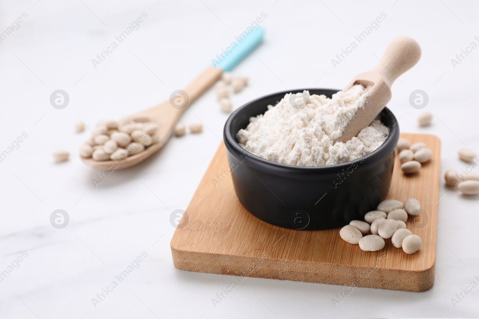 Photo of Bean flour and seeds on white marble table. Space for text