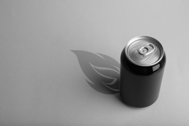 Image of Energy drink and shadow in shape of fire on light grey background 