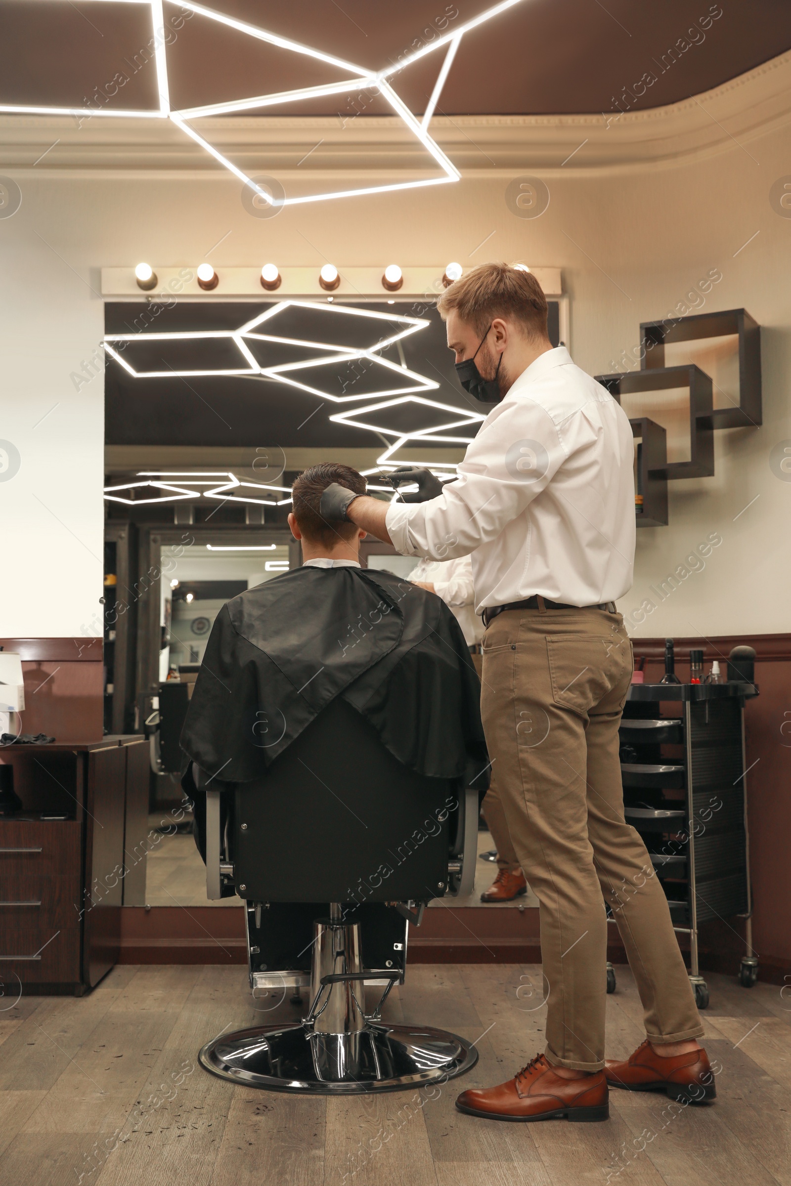 Photo of Professional hairdresser making stylish haircut in salon