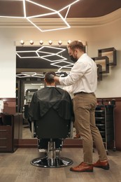 Photo of Professional hairdresser making stylish haircut in salon