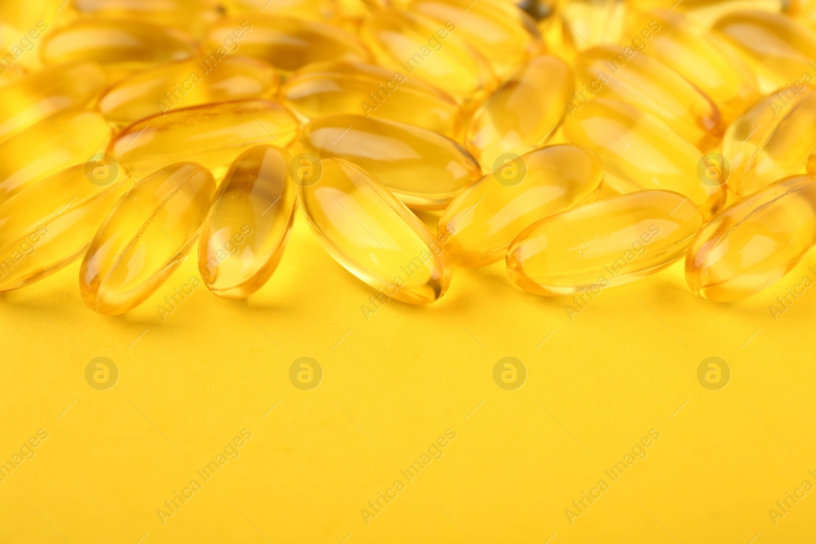 Photo of Many vitamin capsules on yellow background, closeup. Space for text