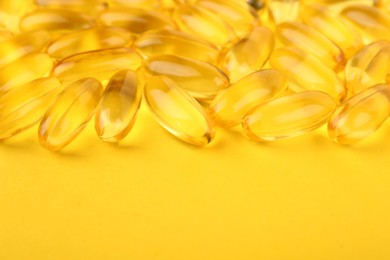 Photo of Many vitamin capsules on yellow background, closeup. Space for text