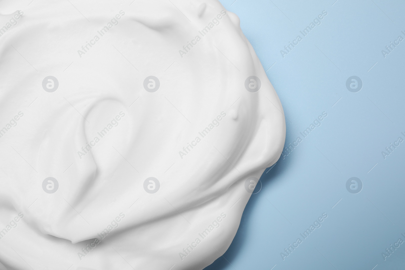 Photo of Sample of shaving foam on light blue background, top view. Space for text