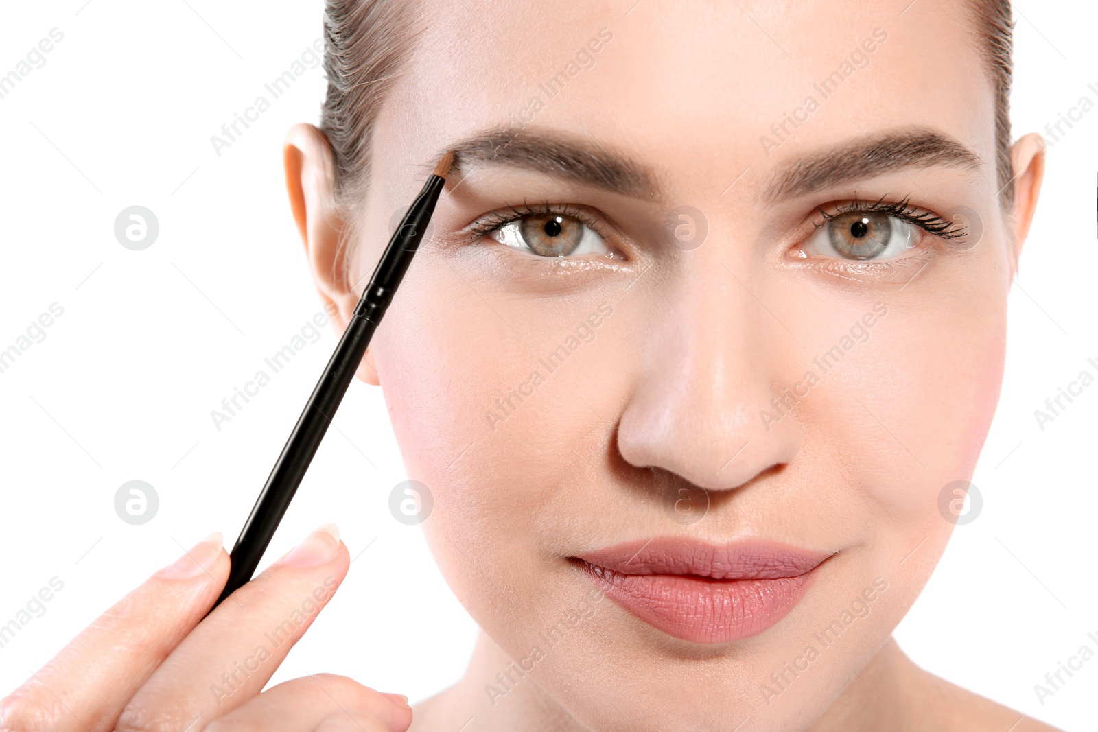 Photo of Beautiful woman with perfect eyebrows applying makeup on light background