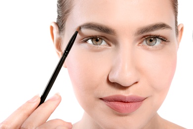 Beautiful woman with perfect eyebrows applying makeup on light background