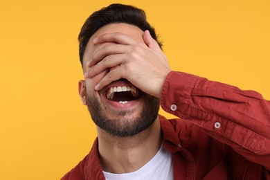 Photo of Young man laughing on yellow background, closeup