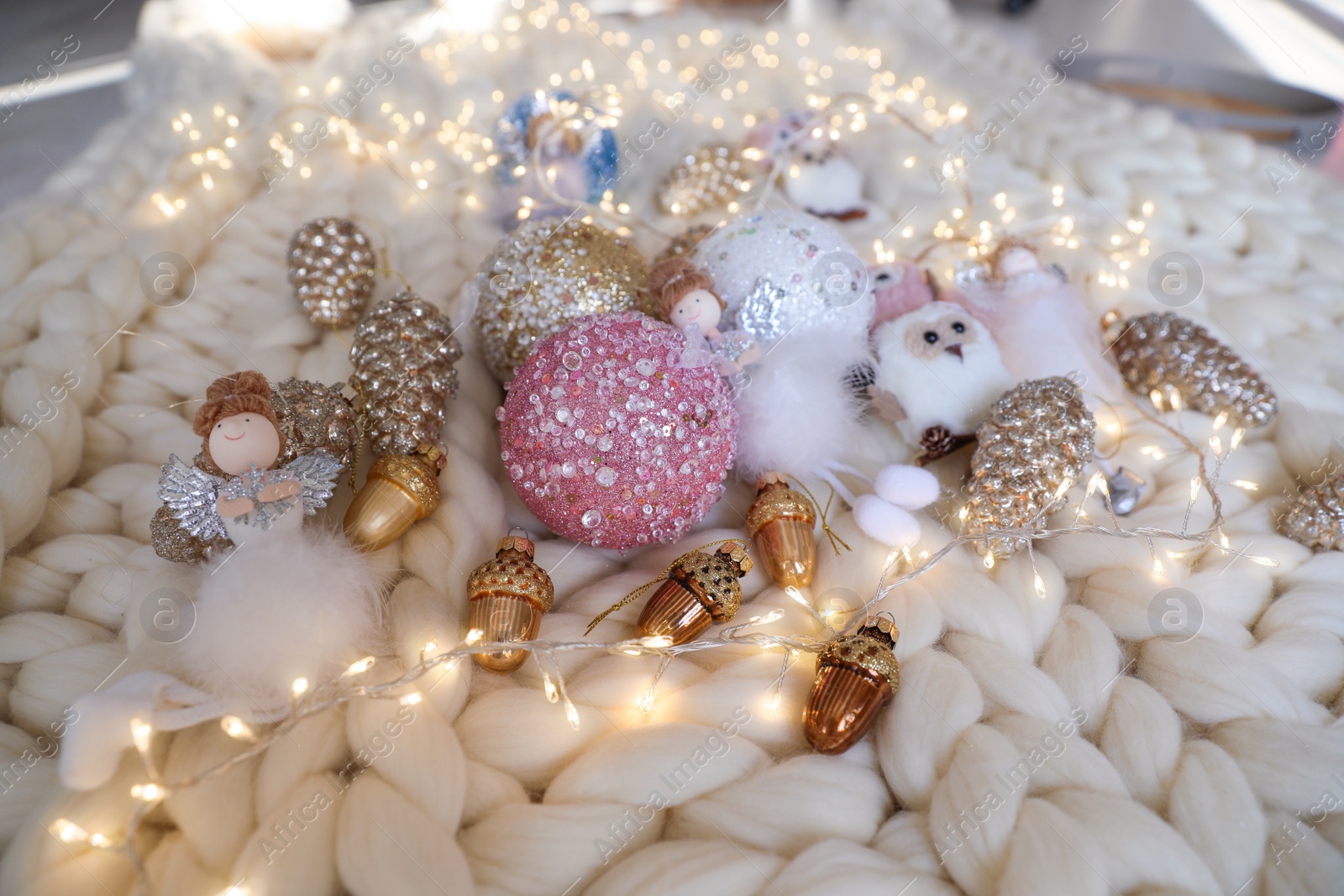 Photo of Beautiful Christmas tree baubles, toys and fairy lights on white knitted fabric