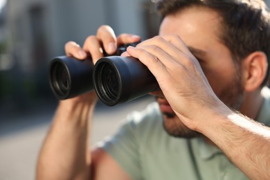 Photo of Concept of private life. Curious man with binoculars spying on neighbours outdoors, closeup