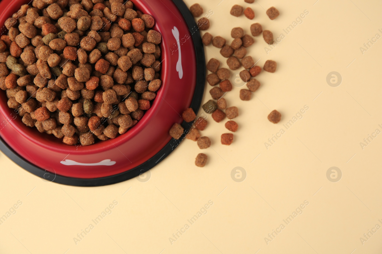 Photo of Dry dog food and feeding bowl on beige background, flat lay. Space for text