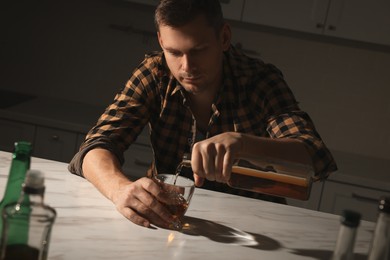 Photo of Addicted man with alcoholic drink at table in kitchen