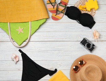 Flat lay composition with swimsuit and beach accessories on wooden background. Space for text