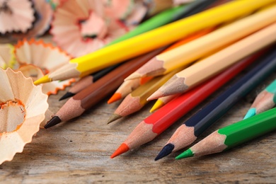 Photo of Color pencils and shavings on wooden table, closeup