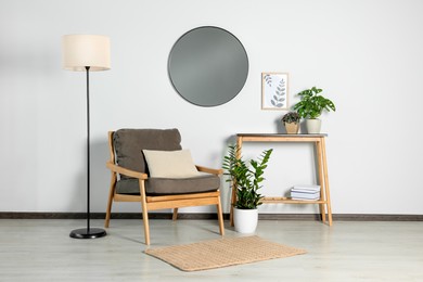 Photo of Stylish living room interior with wooden furniture, houseplants and round mirror on white wall