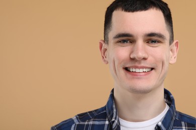 Photo of Handsome young man with clean teeth smiling on beige background, space for text