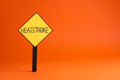 Photo of Sign with words Heat Stroke on orange background, space for text