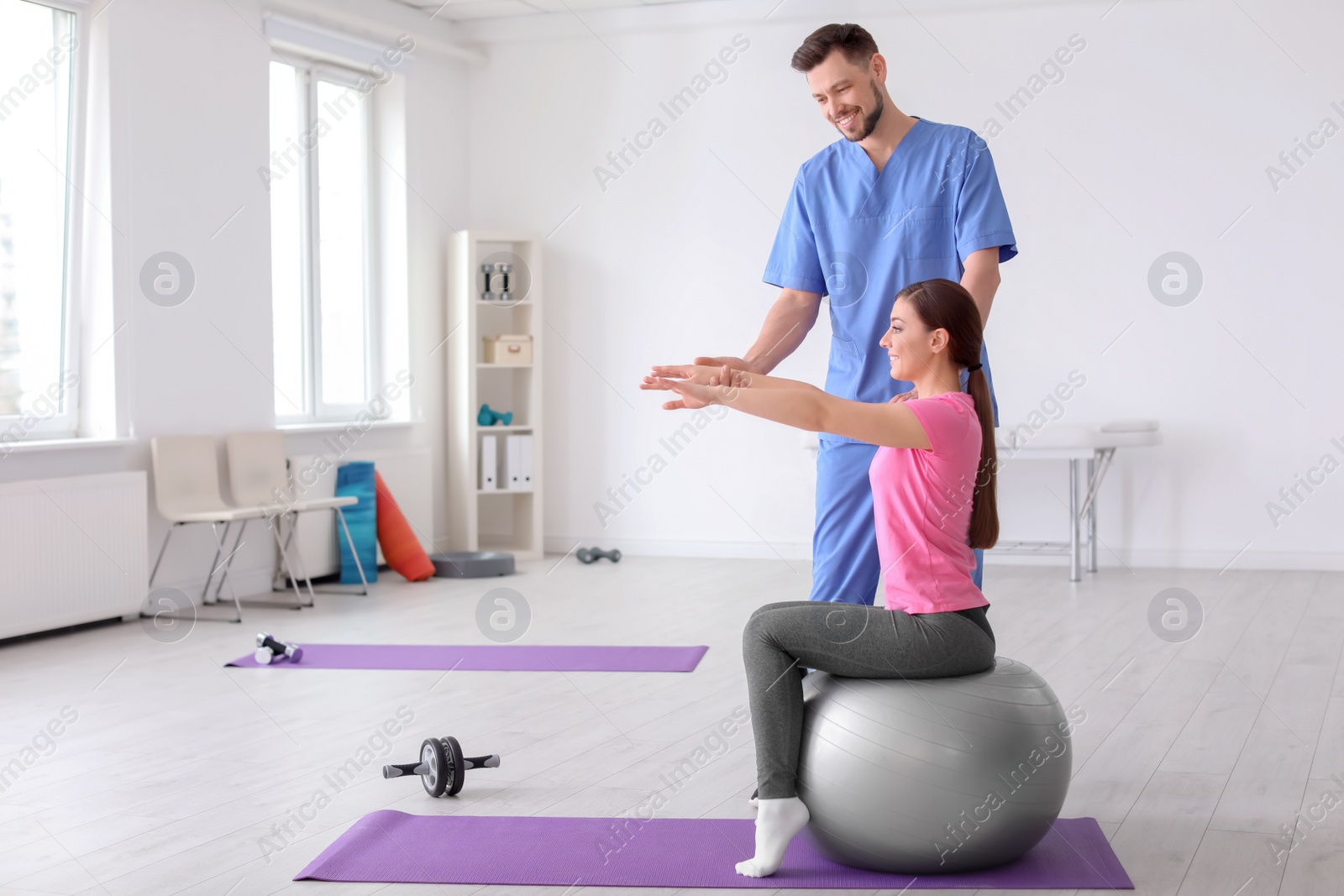 Photo of Physiotherapist working with female patient in clinic