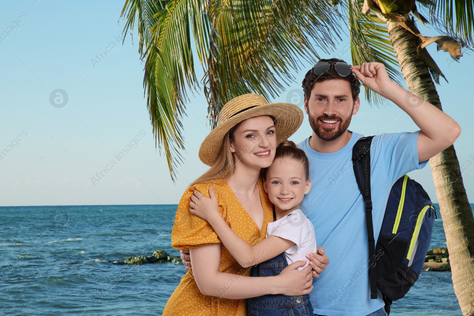 Image of Portrait of happy family with child near palm on beach