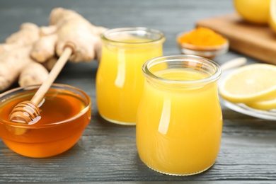 Photo of Immunity boosting drink and ingredients on grey wooden table, closeup