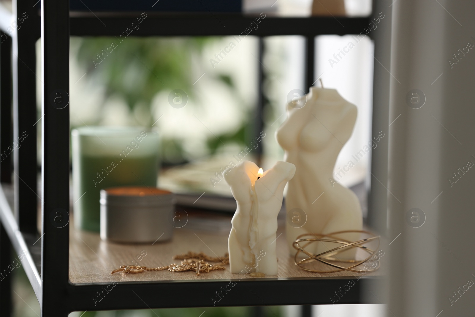 Photo of Beautiful body shaped candles and jewelry on shelf indoors