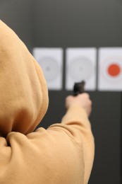 Photo of Man aiming at shooting target indoors, selective focus