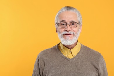 Photo of Portrait of handsome senior man in eyeglasses on orange background
