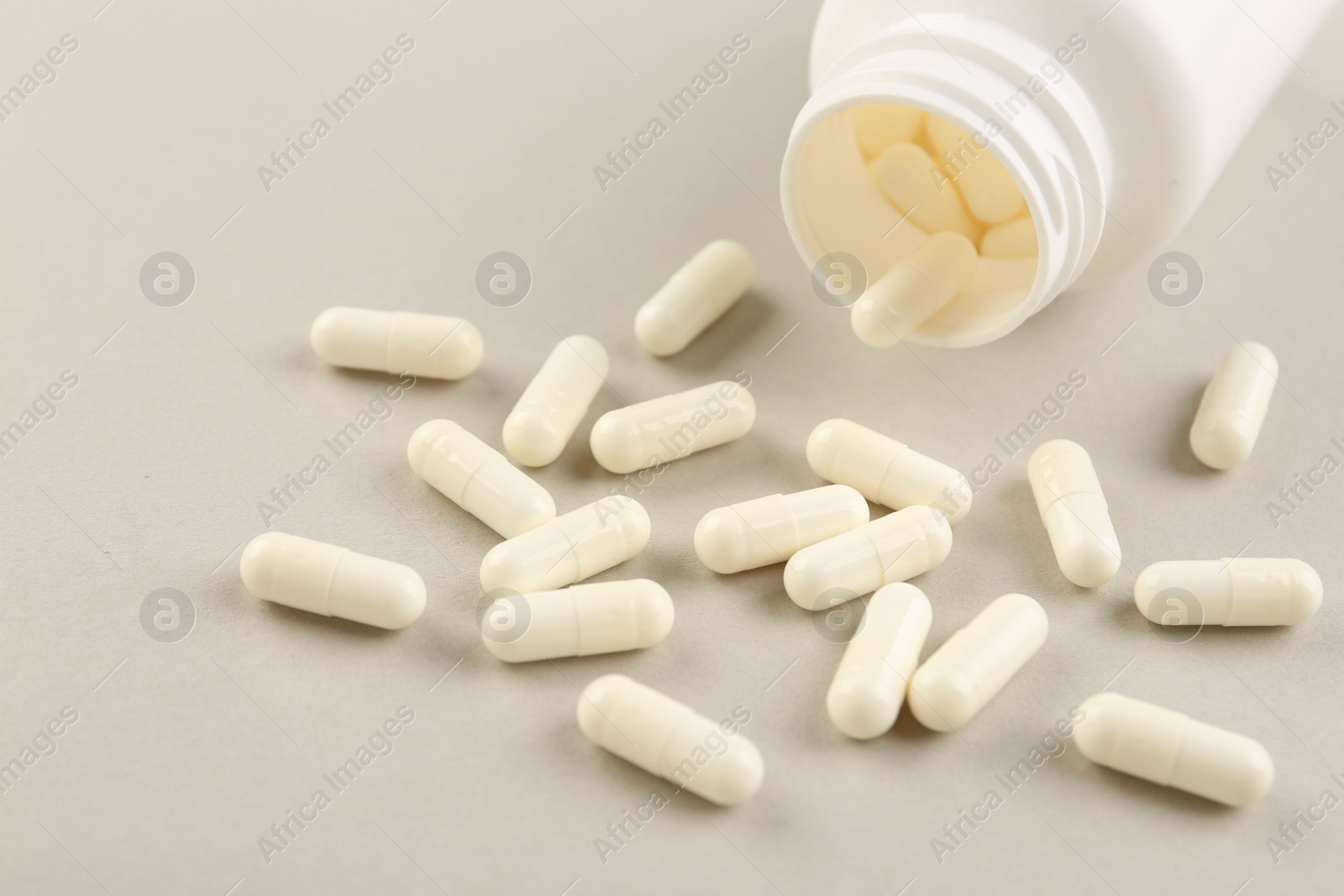 Photo of Bottle and vitamin capsules on light background, closeup