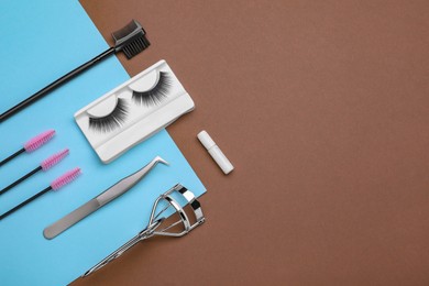 Photo of Flat lay composition with fake eyelashes, brushes and tools on brown background. Space for text