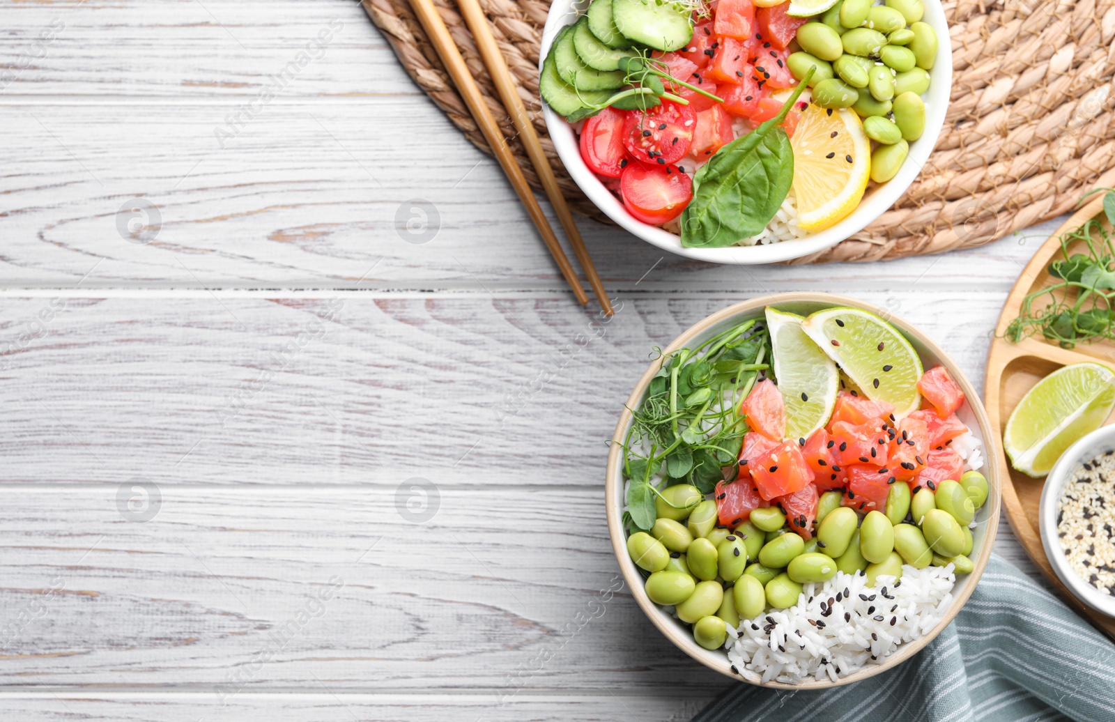 Photo of Delicious poke bowls with fish and edamame beans on white wooden table, flat lay. Space for text