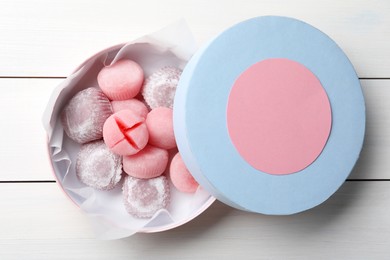 Photo of Many different delicious mochi in box on white wooden table, top view. Traditional Japanese dessert