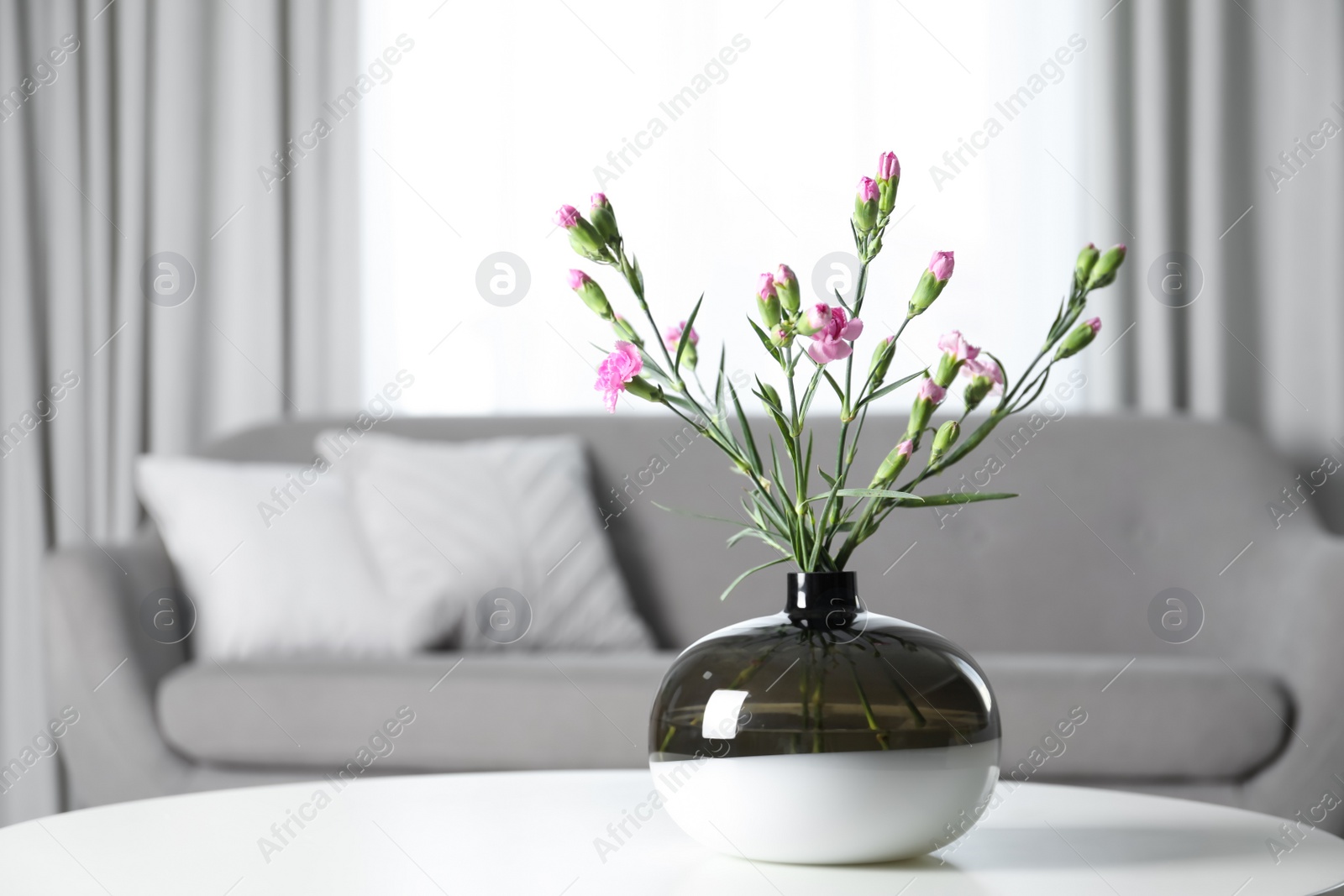 Photo of Vase with beautiful carnation flowers on table in living room, space for text. Stylish element of interior design