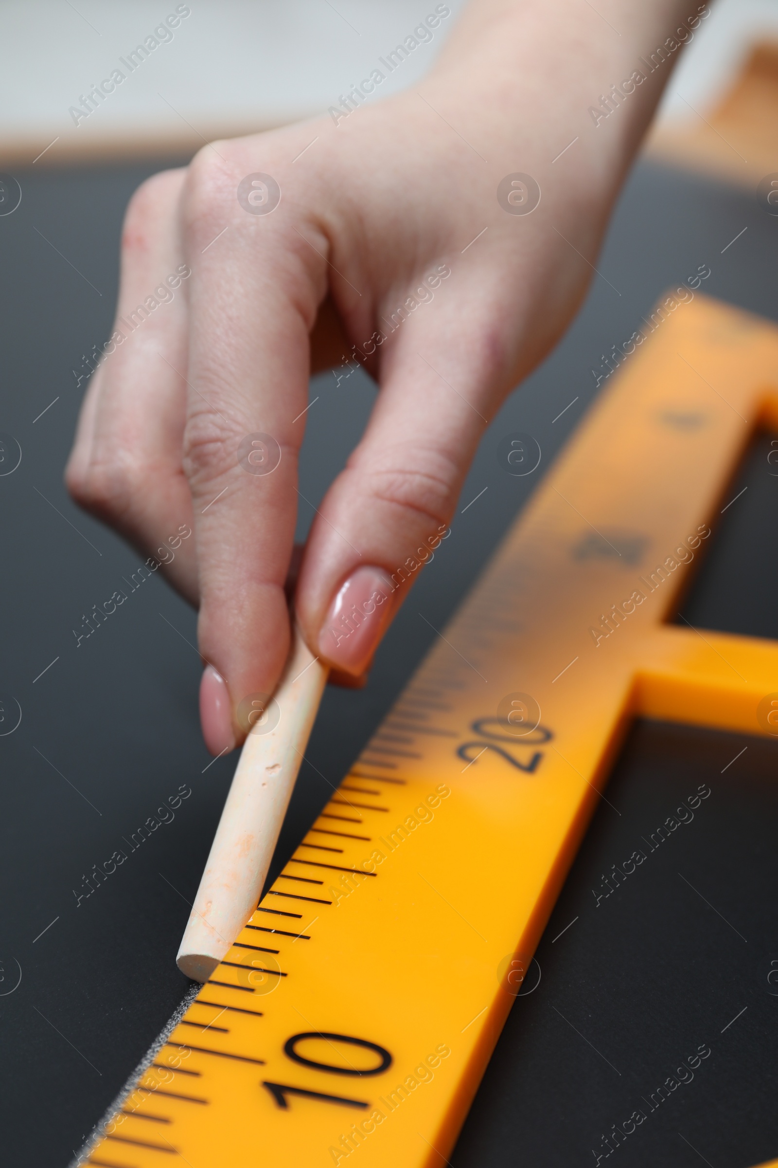 Photo of Woman drawing with chalk and triangle ruler on blackboard, closeup