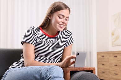 Photo of Happy woman using smartphone on sofa armrest wooden table at home