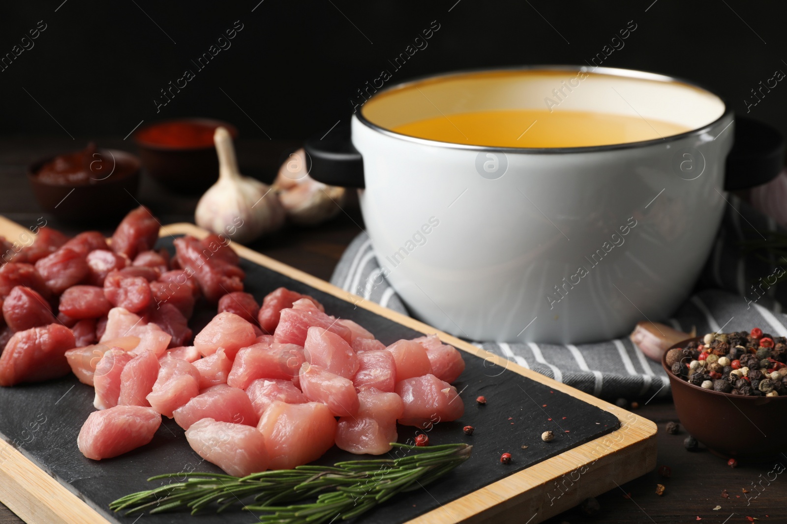 Photo of Board with raw meat fondue pieces and rosemary on table