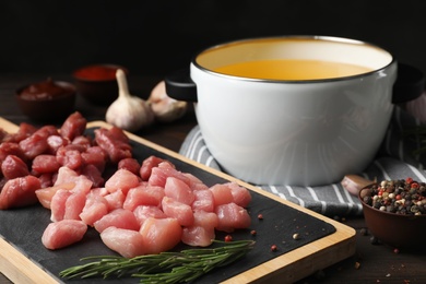 Board with raw meat fondue pieces and rosemary on table