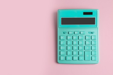 Photo of Turquoise calculator on pink background, top view. Space for text