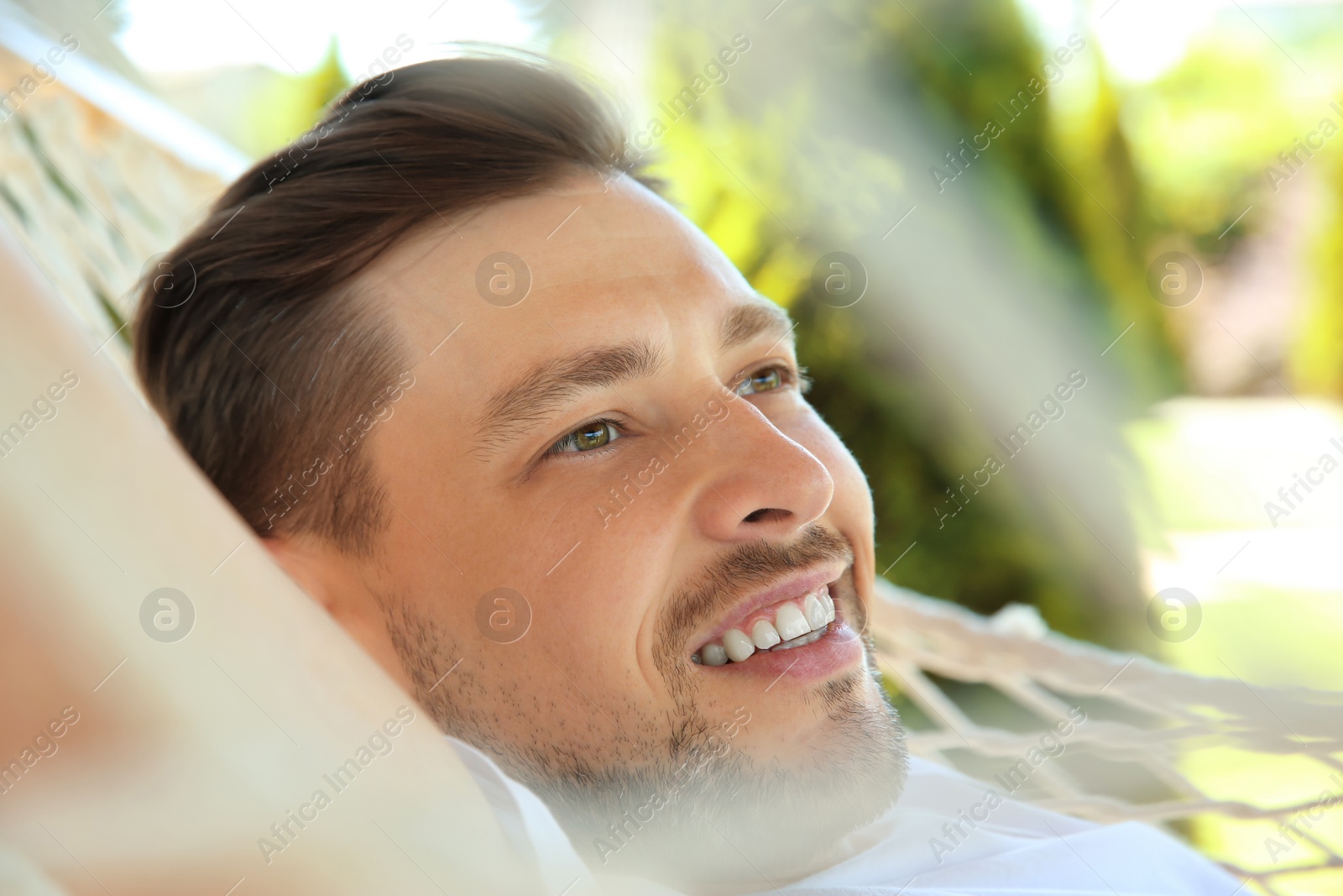 Photo of Man relaxing in hammock outdoors on warm summer day