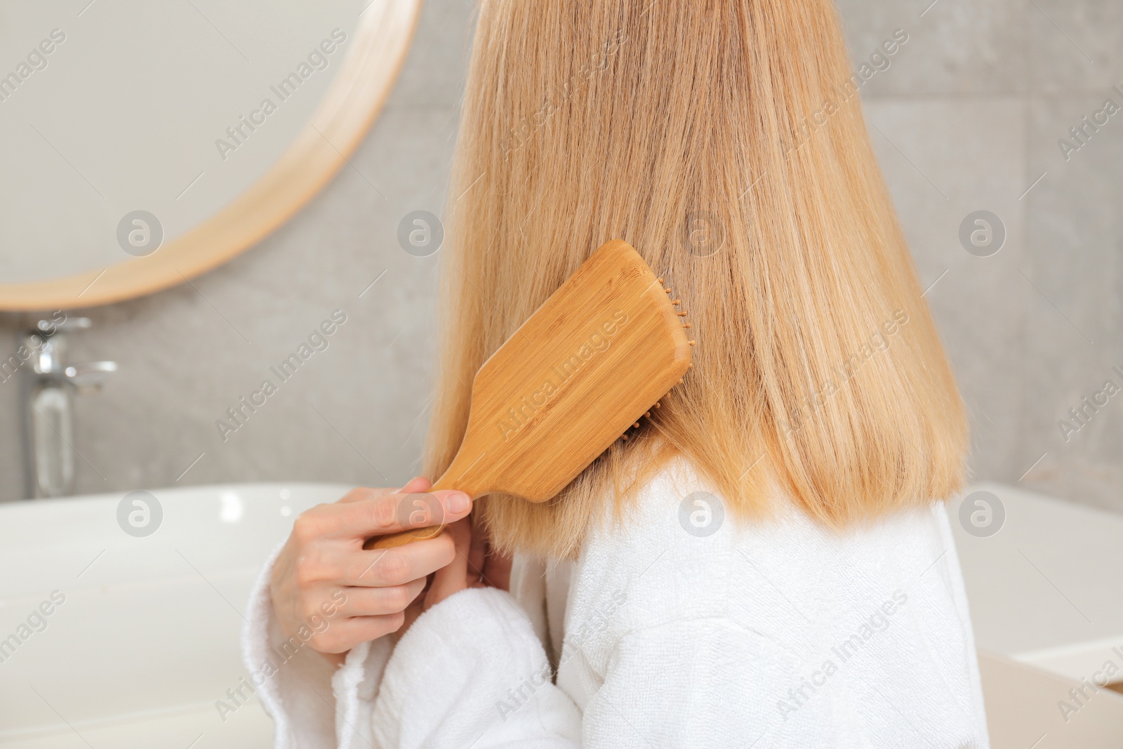 Photo of Woman brushing her beautiful hair in bathroom