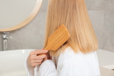 Photo of Woman brushing her beautiful hair in bathroom