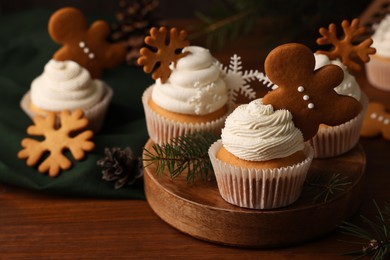 Different beautiful Christmas cupcakes and fir branches on wooden table. Space for text
