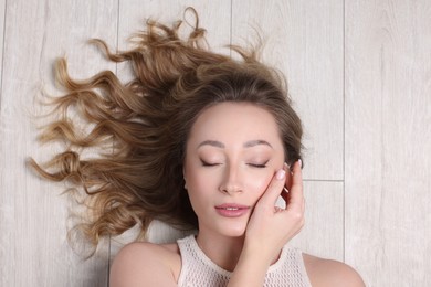 Portrait of beautiful woman with closed eyes on wooden floor, top view