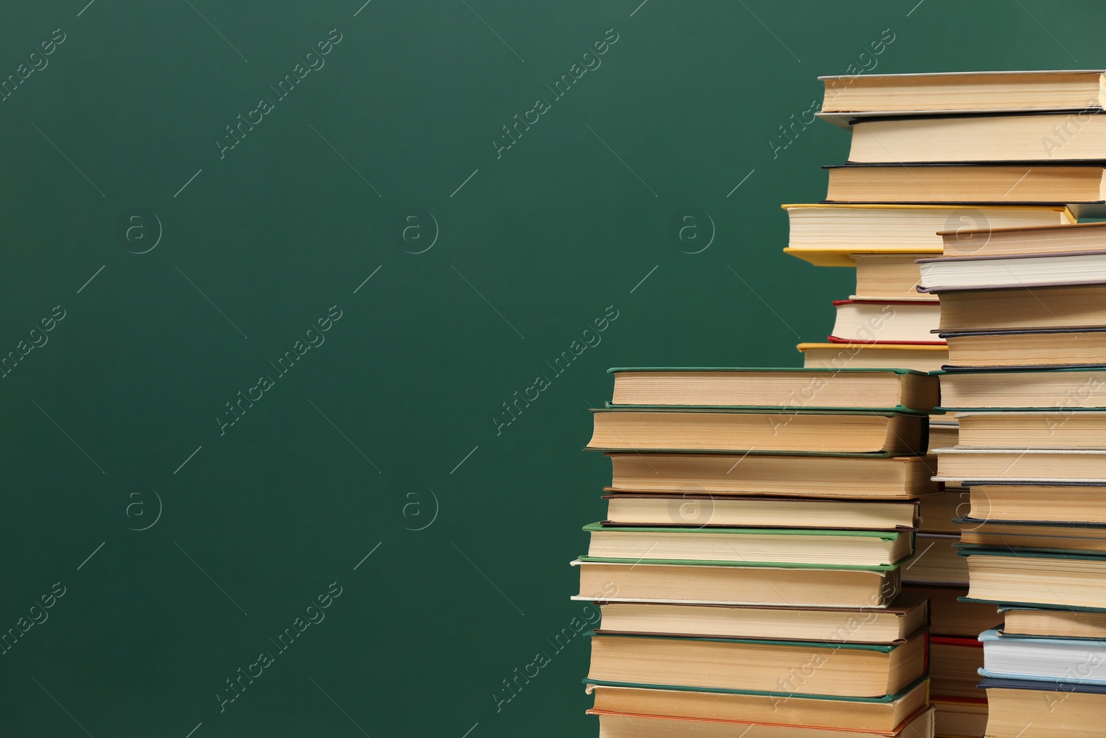 Photo of Many hardcover books near green chalkboard, space for text. Library material