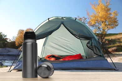 Image of Modern thermos outdoors, space for text. Camping season 