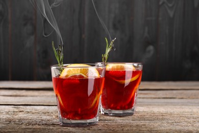 Glasses of delicious refreshing sangria with smoke on old wooden table