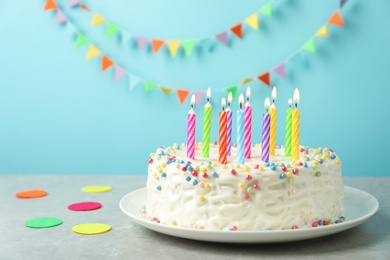 Delicious birthday cake with burning candles on table