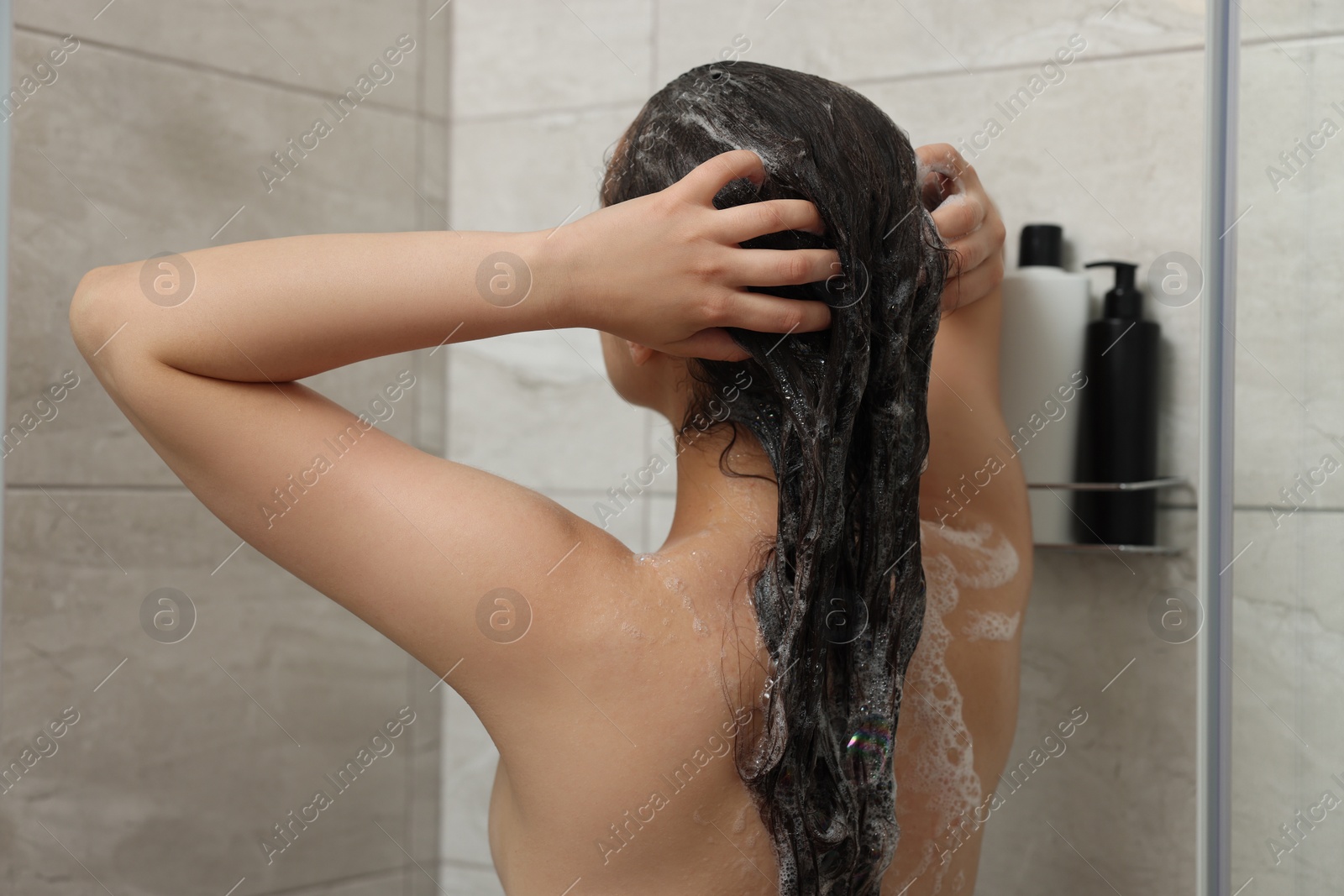 Photo of Woman washing hair in shower, back view