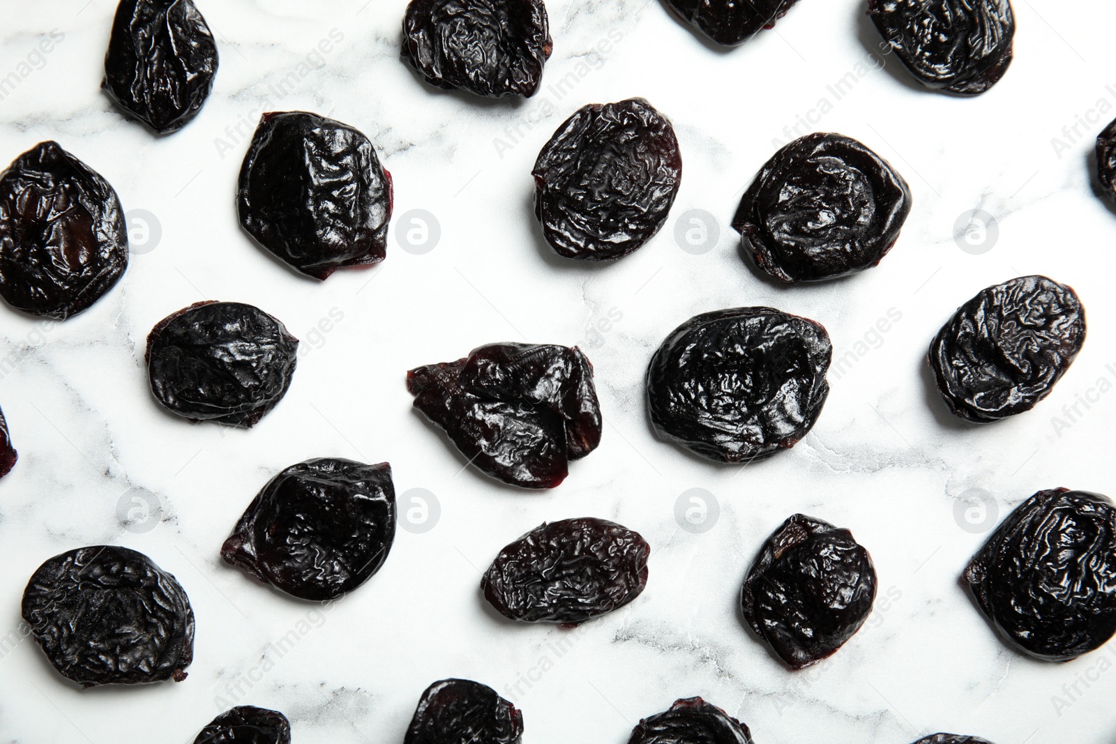 Photo of Flat lay of dried plums on marble background. Healthy fruit