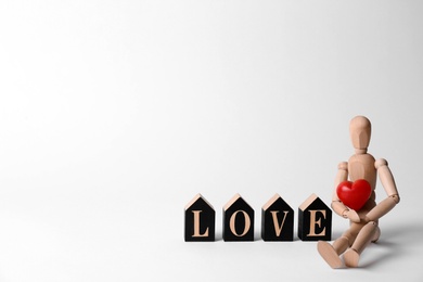 Photo of Word Love made of decorative letters, wooden mannequin and red heart on white background. Space for text